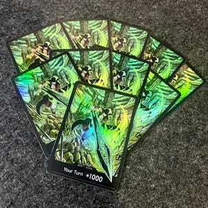 May include: A collection of trading cards featuring a fantasy illustration. The cards have a holographic effect with a green and yellow color scheme. The artwork depicts a figure with a sword in front of a castle. The text "Your Turn +1000" is visible on the bottom.
