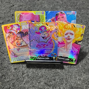 Puede incluir: Una colección de cinco cartas coleccionables de One Piece con Charlotte Linlin y otros personajes. Las cartas muestran ilustraciones vibrantes, detalles holográficos, un nivel de poder de 5000 y texto que incluye el nombre Charlotte Linlin.