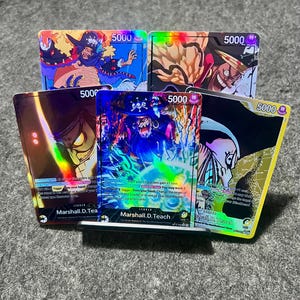 Puede incluir: Cinco cartas coleccionables con ilustraciones coloridas de personajes de anime. Cada carta muestra el número "5000". Las cartas tienen detalles holográficos y están sobre un fondo neutro. El nombre "Marshall.D.Teach" es visible.