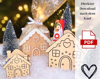 May include: Wooden gingerbread house ornaments with white icing details, windows, and heart-shaped cutouts. A small Christmas tree and a candy bar are in the background. The image also includes the text "Direkter Download nach dem Kauf" and a PDF icon.