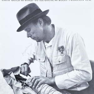 Könnte beinhalten: Schwarz-weiß-Plakat, das die Veranstaltung "Incontro con Beuys" in der Galleria Lucrezia De Domizio in Pescara ankündigt. Es zeigt einen Mann mit Hut und Jacke, der mit einem verpackten Objekt arbeitet. Das Datum der Veranstaltung ist der 3. Oktober 1974.