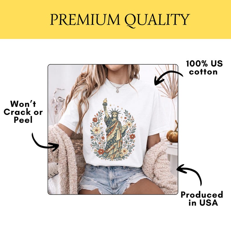 May include: White t-shirt featuring a graphic of the Statue of Liberty surrounded by flowers. The shirt is made of 100% US cotton and is produced in the USA. The graphic design won't crack or peel.