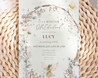 May include: A winter-themed invitation with the text "IT'S A WINTER ONElubul LUCY is turning ONE" and event details. The design features floral and fairy illustrations, with a Canva editable template logo in the upper right corner. The invitation is set on a woven mat.