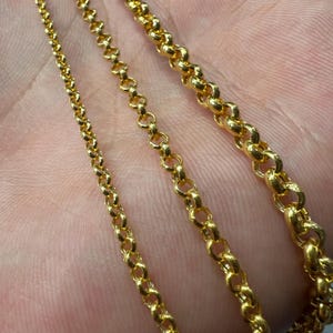 May include: Three gold-toned metal chains of varying thicknesses, each featuring a classic round cable link design. The chains are arranged side-by-side, showcasing the difference in link size from the thinnest chain on the left to the thickest on the right.