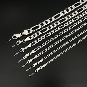 Peut inclure: Une collection de sept chaînes Figaro argentées disposées en diagonale par taille, avec des fermoirs mousqueton. Les largeurs sont indiquées comme 11mm, 9mm, 6.50mm, 5.50mm, 4.50mm, 3.50mm et 2.85mm, montrant l'épaisseur variable de chaque chaîne.