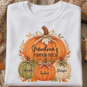 May include: A white crew neck t-shirt featuring a graphic of four pumpkins with bows. The large central pumpkin has the text Grandma's PUMPKIN PATCH. Three smaller pumpkins below are labeled with the names Joseph, Sophia, and Harper.