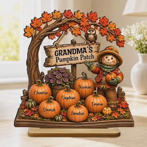 May include: A decorative tabletop display featuring a tree with orange and red autumn leaves, an owl, and a sign reading "GRANDMA'S PUMPKIN PATCH." A scarecrow stands beside pumpkins labeled with the names Charlie, Thomas, Sophia, David, Emma, and Amelia.