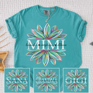 Peut inclure: T-shirt turquoise avec un motif floral coloré et le mot "MIMI" en blanc, ainsi que des noms. D'autres modèles montrent "NANA", "GRANDMA" et "GIGI" avec des noms. Un collier argenté est visible.