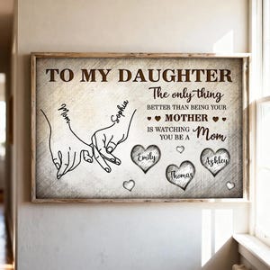 May include: A framed print with a light wood grain border. The text reads "TO MY DAUGHTER" and "The only thing better than being your MOTHER is watching you be a Mom." Includes names in hearts.