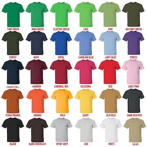 May include: A selection of crew neck t-shirts in a variety of colours, including green, blue, red, and neutral tones. Each shirt is displayed with its colour name, such as "Turf Green," "Navy," and "Red." The shirts are arranged in rows and columns, showcasing a wide range of options.