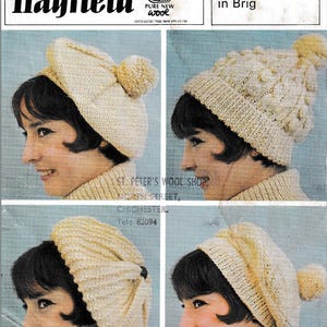 May include: Vintage advertisement showcasing four cream-coloured Aran-style knitted hats. The hats display varied textures and pom-poms. The advertisement includes the Hayfield logo and the text "knit into fashion-with". The text "Aran type Hats in Brig" is also visible.