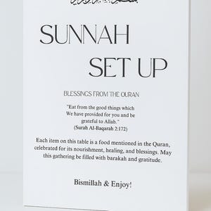 May include: A white rectangular sign with black text. The sign says "SUNNAH SET UP" and includes Arabic script at the top. It features a quote from the Quran and the phrase "Bismillah & Enjoy!"