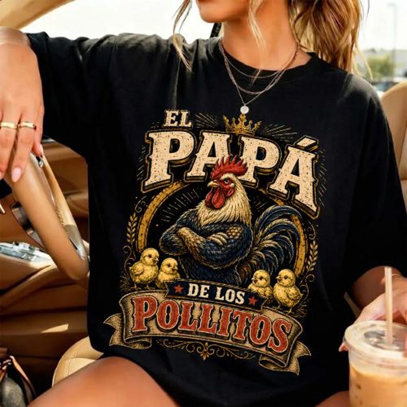 May include: A black t-shirt featuring a graphic print of a rooster wearing a crown with its wings crossed, surrounded by four small chicks. The text reads EL PAPA DE LOS POLLITOS in a distressed, vintage-style font with decorative flourishes.
