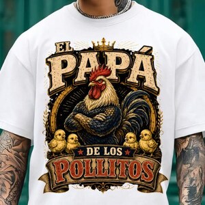 May include: A white t-shirt featuring a graphic print of a rooster with crossed wings wearing a crown, surrounded by four small yellow chicks. The text reads EL PAPA DE LOS POLLITOS in a bold, vintage-style font with decorative banner elements.