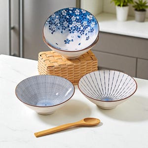 Puede incluir: Un juego de cuatro cuencos de cerámica con diseños florales y geométricos en azul y blanco. Un cuenco tiene un diseño floral, otro tiene líneas verticales y un tercero tiene un patrón de puntos. Una pequeña cuchara de madera descansa frente a los cuencos.