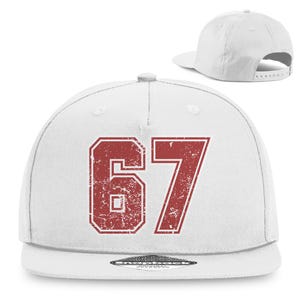 Könnte beinhalten: Weiße Baseballkappe mit flachem Schirm, auf der die Zahl "67" in einem verblichenen roten Schriftzug abgebildet ist. Die Kappe wird aus verschiedenen Blickwinkeln gezeigt, einschließlich der Vorder- und Rückseite, mit verstellbarem Riemen.