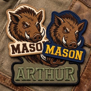 May include: Three embroidered patches featuring a brown wild boar head with tusks. Two patches display the name MASON in brown and yellow text respectively, while the third patch at the bottom displays the name ARTHUR in olive green text.
