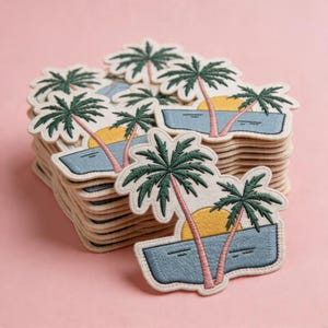 May include: A stack of embroidered patches featuring a tropical sunset scene. Each patch has a palm tree, a yellow sun, and blue water. The patches have a cream-colored border and are stacked on a pink background.