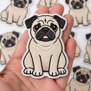 May include: An embroidered patch featuring a tan pug with black ears and a black muzzle. The dog has large brown eyes and a small pink tongue visible. The patch has a white stitched border and is shaped to follow the outline of the sitting pug.