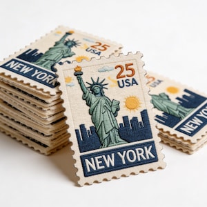 May include: Embroidered patches featuring the Statue of Liberty, a sun, and a cityscape. The patches are rectangular with a postage stamp design, the text "NEW YORK" and "25 USA". A stack of patches is visible.