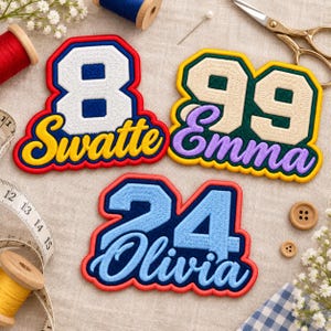 May include: Three embroidered patches featuring numbers and names. One patch shows the number 8 and the name Swatte in yellow. Another shows 99 and Emma in purple. The third shows 24 and Olivia in blue. Each patch has a thick, colorful border.