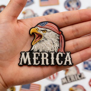 May include: Embroidered patch featuring a bald eagle with a red, white, and blue American flag bandana. The word "MERICA" is stitched in white on a black background. Patriotic theme.