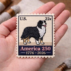 May include: A rectangular patch featuring a black, white, and tan dog, resembling a stamp. The text "U.S." and "22¢" are at the top. The bottom text reads "America 250 - 1776-2026". The patch has a decorative, scalloped edge.