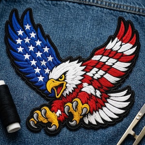 May include: An embroidered patch of a bald eagle with wings spread wide. The left wing features a blue field with white stars, while the right wing and body display red and white stripes. The eagle has a white head, yellow beak, and yellow talons.