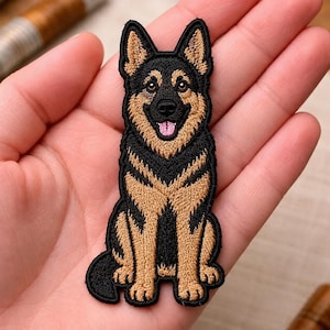 May include: An embroidered patch featuring a German Shepherd dog in a sitting position. The dog has black and tan fur, pointed ears, and an open mouth showing a pink tongue. The embroidery uses detailed stitching to define the facial features.