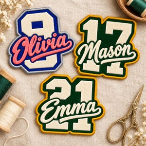 May include: Three embroidered varsity-style patches featuring numbers and names. One patch shows the number 9 with the name Olivia in pink. Another shows 17 with the name Mason in white. The third shows 21 with the name Emma in white.