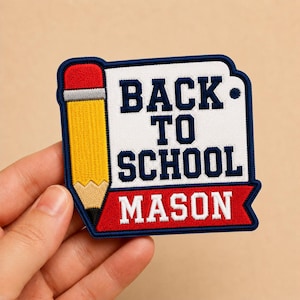 May include: Embroidered patch with a yellow pencil and the words "BACK TO SCHOOL MASON" in navy blue and red. The patch has a white background and a navy blue border. Perfect for backpacks or jackets.