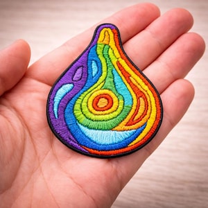May include: Embroidered patch in a teardrop shape, featuring a vibrant rainbow design. The patch has a black border and showcases a spectrum of colors, including purple, blue, green, yellow, and orange. This decorative patch is suitable for clothing or accessories.