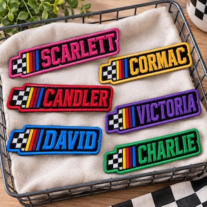 May include: Six rectangular embroidered patches featuring names in bold block letters: SCARLETT, CORMAC, CANDLER, VICTORIA, DAVID, and CHARLIE. Each patch includes a black and white checkered pattern and a vertical multi-colored stripe design.