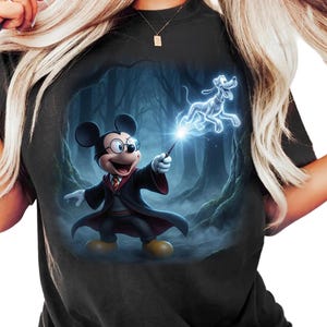 May include: Black t-shirt featuring a cartoon image of Mickey Mouse dressed as a wizard, holding a wand with a glowing effect. A ghostly image of Pluto is also present. The background depicts a dark forest scene.