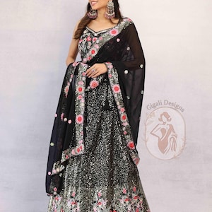Peut inclure: Une robe de soirée noire à paillettes avec broderie florale rose, rouge et verte. La robe est accompagnée d'un châle noir transparent assorti avec une bordure florale. L'image comprend également le texte "Gigali Designs".