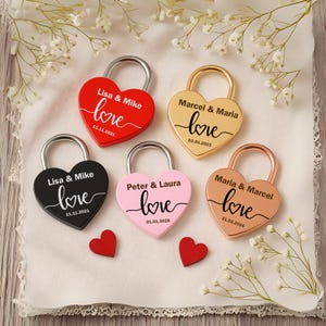 Puede incluir: Candados en forma de corazón en rojo, negro, dorado, rosa y cobre, personalizados con nombres y fechas. Cada cerradura presenta la palabra "love" en cursiva. También hay dos pequeñas decoraciones en forma de corazón rojo.