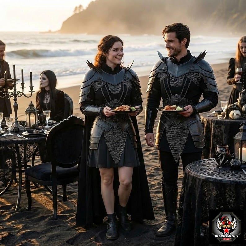 May include: Two people in black armor, holding plates of food, stand on a beach. The armor features intricate metal detailing and shoulder spikes. A black cape and skirt are visible. Tables set with black tablecloths and candles are in the background. The scene evokes a medieval fantasy theme.