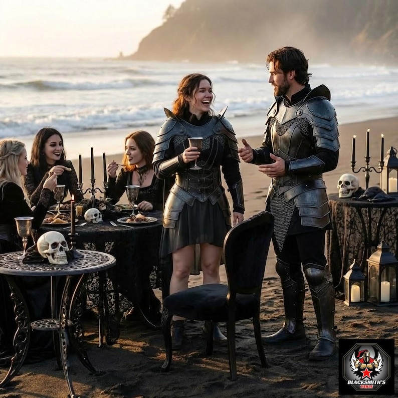 May include: A group of people in medieval armor and gothic attire are gathered on a beach. They are seated at tables with skulls and candles, enjoying a meal. The scene evokes a fantasy or historical theme.