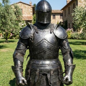 May include: A full suit of medieval armor in dark gray, including a helmet, chest plate, and arm and leg protection. The armor is detailed with rivets and straps, and is displayed on a grassy lawn with a building in the background.