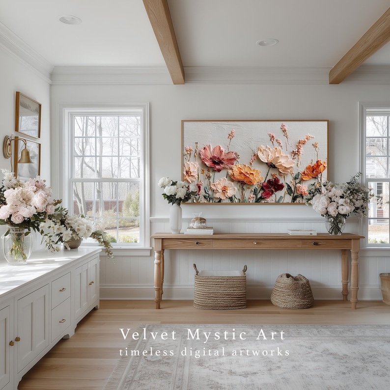 May include: A light-filled room with a large floral painting as the focal point. The artwork features textured, colorful flowers in shades of pink, orange, and red. A wooden console table, baskets, and fresh flower arrangements complement the artwork. The text "Velvet Mystic Art" is visible.