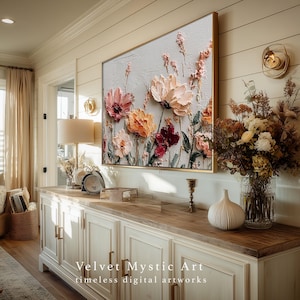 May include: A framed floral artwork with textured, raised paint. The flowers are in shades of pink, orange, and burgundy against a light gray background. The frame is gold. The artwork is displayed above a white cabinet. Text on the bottom reads "Velvet Mystic Art timeless digital artworks."