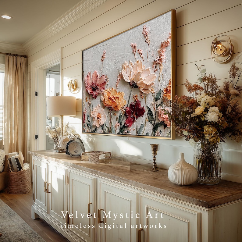 May include: A framed floral artwork with textured, raised paint. The flowers are in shades of pink, orange, and burgundy against a light gray background. The frame is gold. The artwork is displayed above a white cabinet. Text on the bottom reads "Velvet Mystic Art timeless digital artworks."