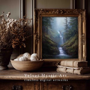 May include: A framed landscape painting of a waterfall cascading through a lush green forest. The painting is in an ornate gold frame, displayed on a wooden surface with a bowl of yarn, dried flowers, and a stack of books. The text "Velvet Mystic Art" is visible.