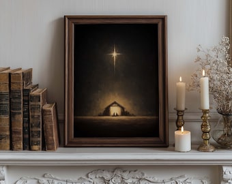 May include: A framed art print depicting a Nativity scene with a bright star above a stable. The artwork is in a dark, warm color palette, with a wooden frame. The print is displayed on a white mantelpiece, alongside lit candles and old books.