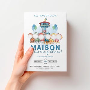 Op de afbeelding: Een rechthoekige verjaardagsuitnodiging met de tekst ALL PAWS ON DECK! boven een illustratie van een uitkijktoren en zes honden met lege witte cirkelvormige gezichten. Daaronder staat MAISON turning three! JOIN US TO CELEBRATE SATURDAY 10 MAY 2026 AT 2-4 PM 12345 RESCUE BAY, TRAVERSE CITY, NY 49684 RSVP TO EZRA 123-456-7890.