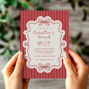 May include: A red and white striped invitation for a Galentine's Brunch. The invitation has a decorative border with bows and the text "YOU'RE INVITED TO A Galentine's Brunch". The invitation is held by a person.