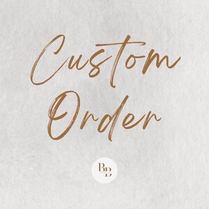 May include: A light beige background with the words "Custom Order" in a flowing, brown script. A small, circular logo with the initials "BD" is at the bottom. The image has a textured, paper-like appearance.