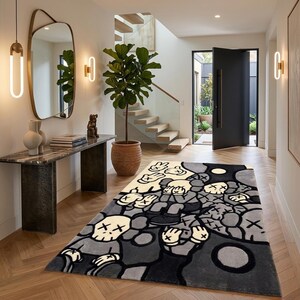 May include: A rectangular area rug featuring a repeating graphic pattern of cartoon-style characters with X-shaped eyes and gloved hands in a palette of cream, light gray, dark gray, and black, laid out on a light-colored wooden floor.