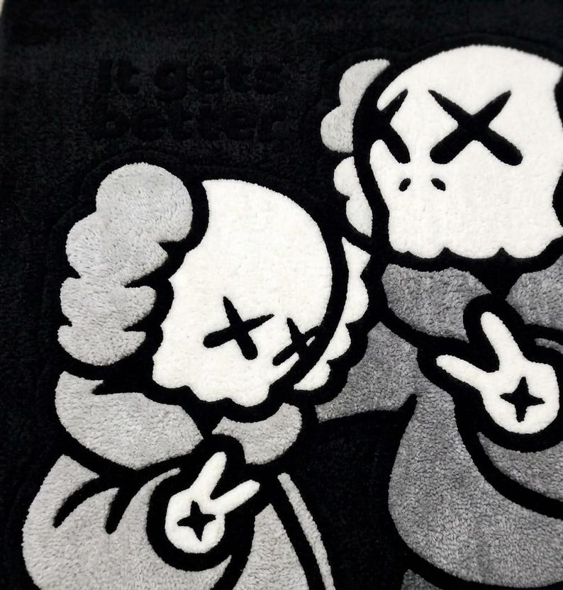 K&ouml;nnte beinhalten: Ein getufteter Teppich in Schwarz, Wei&szlig; und Grau mit zwei cartoonartigen Figuren, die X-f&ouml;rmige Augen und Friedenszeichen an den H&auml;nden haben. Der Text 'it gets better' ist in der oberen linken Ecke auf dunklem Grund eingestickt.