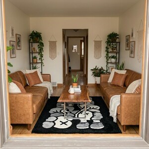 K&ouml;nnte beinhalten: Ein Wohnzimmer mit zwei braunen Ledersofas, die sich gegen&uuml;berstehen, einem Couchtisch aus Holz mit Naturkante und einem schwarzen Teppich mit einer wei&szlig;en und grauen Cartoon-Grafik. Der Raum enth&auml;lt Topfpflanzen und Wandbilder.